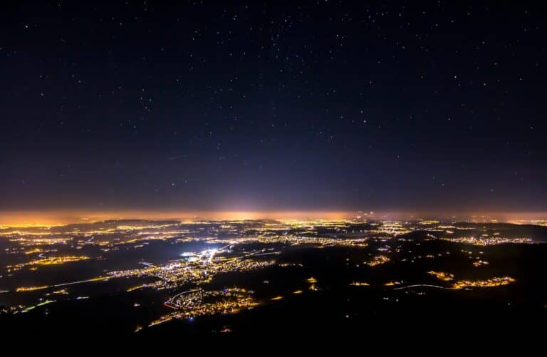 Un ciel étoilé au-dessus d'une vue aérienne des lumières d'une ville pendant la nuit.