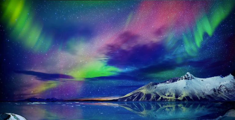 Une aurore boreale se reflete sur l’ocean et les montagnes enneigees