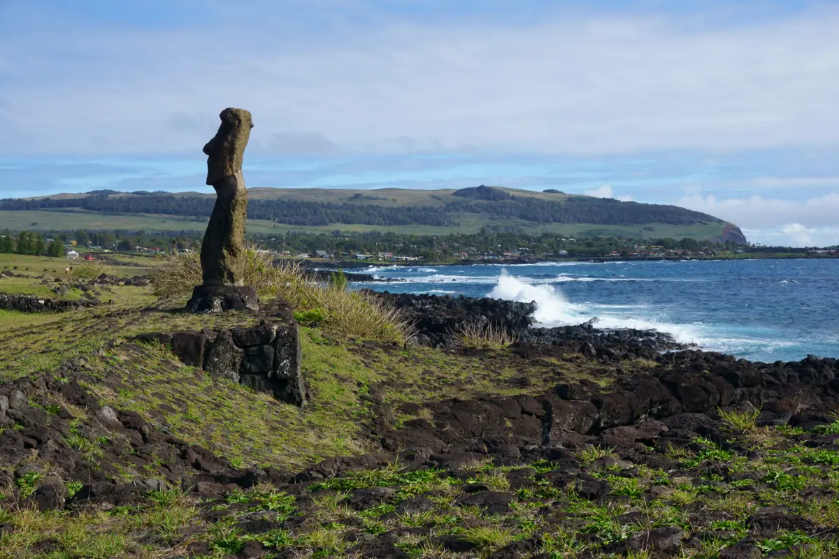Un moaï de l'île de Pâques, avec la ville d'Hanga Roa en arrière-plan.
