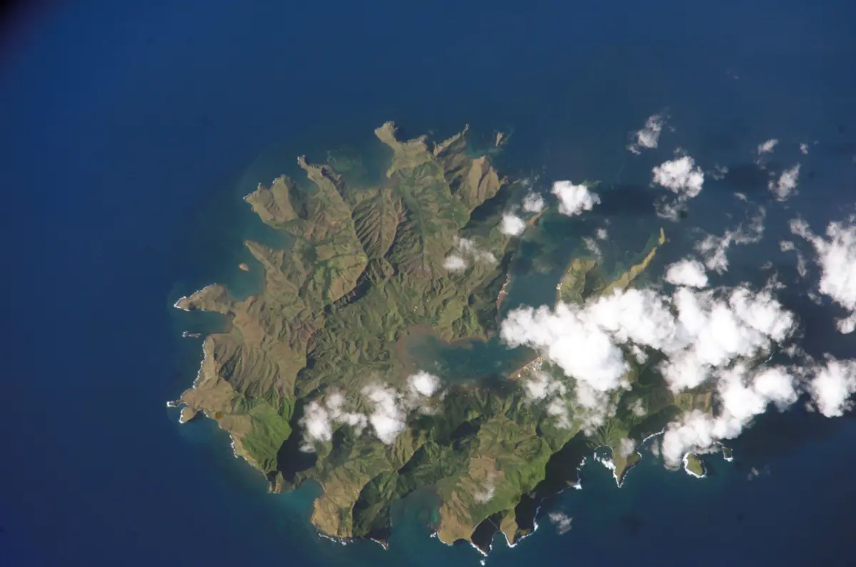 Vue aérienne de Rapa Iti, une île volcanique circulaire traversée par une large baie.